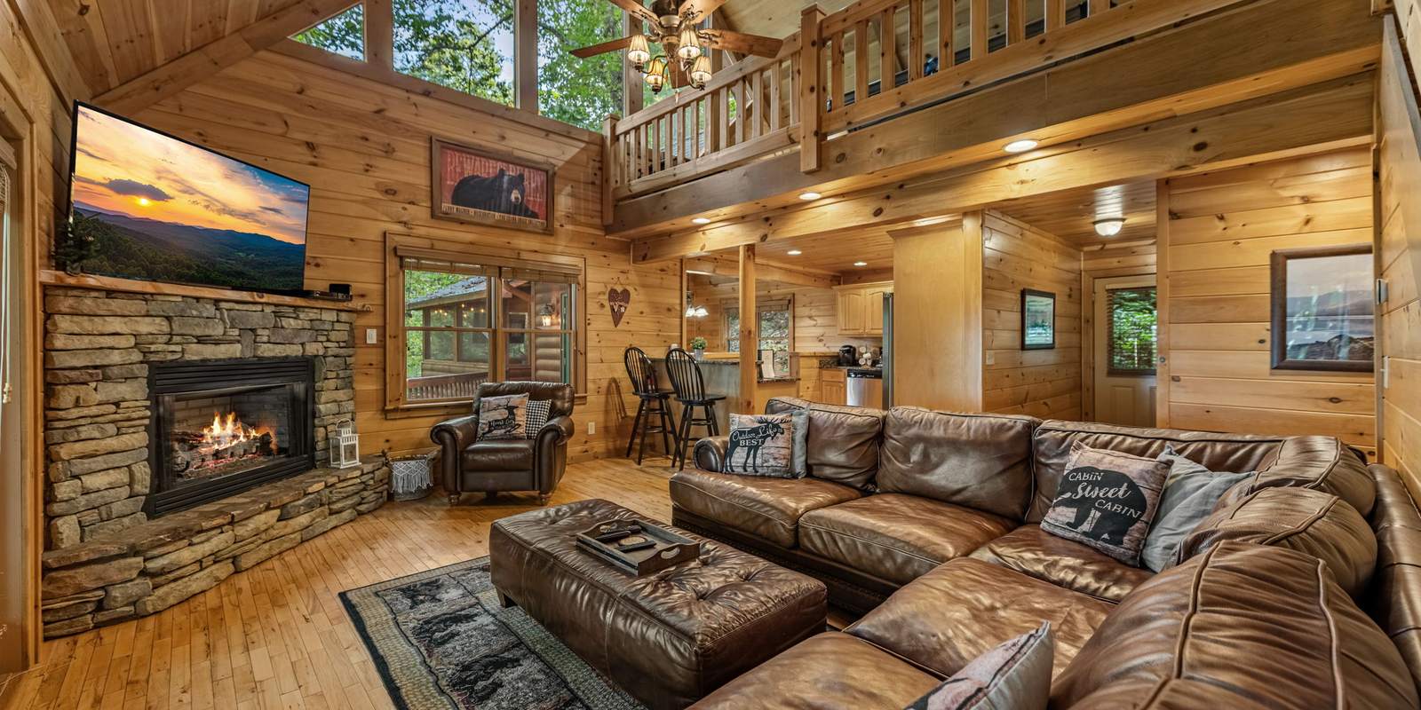 Living room with leather sectional and the stone gas fireplace lit
